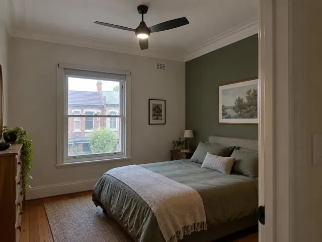 Bedroom with a black ceiling fan, green feature wall, bed and window in Petersham