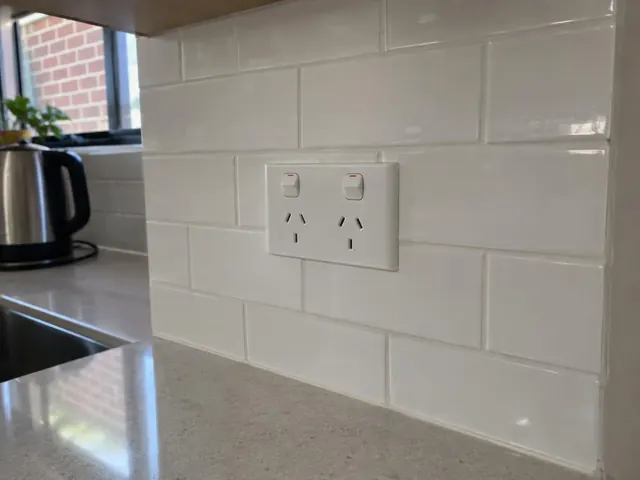Double power point on white tiled kitchen splashback above a benchtop in Marrickville