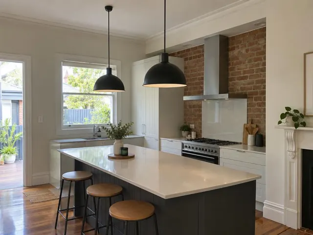 Kitchen with two black pendant lights over a white island, brick splashback and timber floor in Petersham
